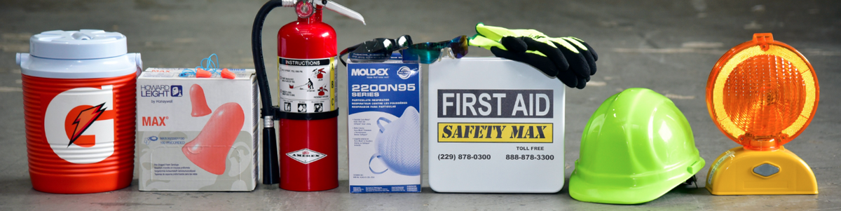 A first aid and safety equipment kit arranged on a gray concrete floor, including a red Gator cooler, a red fire extinguisher, a first aid box, a hard hat, gloves, and a yellow/orange safety beacon light.